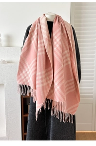 Detail of pink and white plaid scarf with long fringes over a grey coat on a mannequin