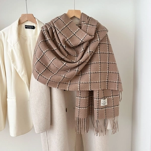 Classic brown plaid cashmere-like scarf with tassels over a stylish wool coat
