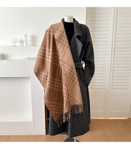 Detail of classic brown plaid cashmere scarf with soft tassels and elegant grey wool coat