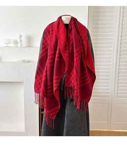 Detailed view of red plaid cashmere scarf with fringes worn over a dark grey wool coat