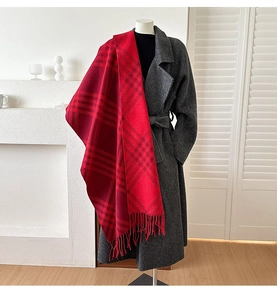 Detail of red plaid scarf with fringes styled over a long grey wool coat for winter fashion