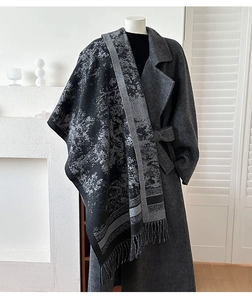 Detail of a black and grey patterned shawl with fringes on a wool coat outfit