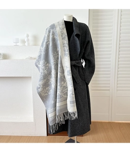 Detail of gray forest pattern scarf with fringe, layered over a long wool coat