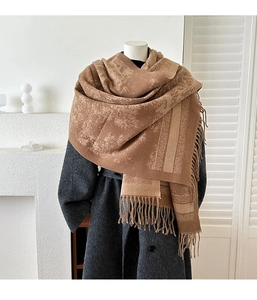 Detail of vintage jacquard scarf with long tassels draped over a wool coat for winter