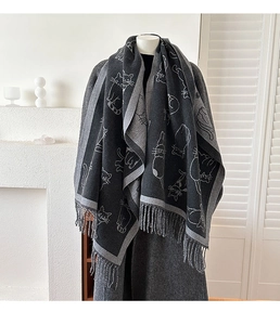 Close-up of thick dark grey cashmere-like scarf featuring white cat patterns and fringe