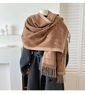 Close-up of brown winter scarf with cat jacquard pattern and tassel detail on a mannequin