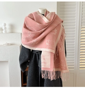 Close-up of pink cashmere-like scarf with white cat jacquard pattern and fringe edge