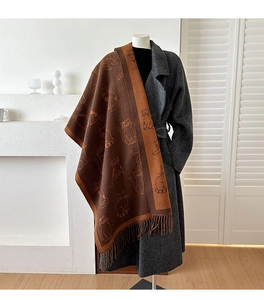 Detail of knitted cat pattern jacquard scarf with fringe on a grey wool coat