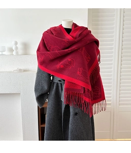 Close-up of deep red jacquard cat pattern scarf with long tassels on a wool coat