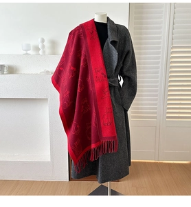 Detail of red jacquard scarf with cat pattern and fringe on gray wool coat