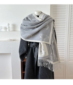 Close-up of grey cat pattern scarf with fringe tassels over a dark grey wool coat