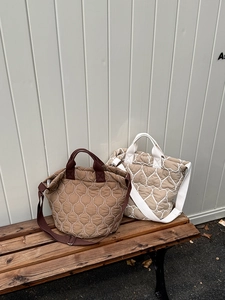 Details gesteppter Tragetaschen in Braun und Beige mit Herzmuster auf einer Holzbank