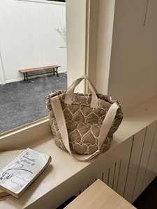 Detail der khakifarbenen Stepptasche mit Herzmuster-Stickerei und breitem cremefarbenem Riemen
