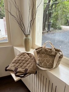 Detail von gesteppten Puffer-Taschen mit Herz- und Wellenmuster auf einer Fensterbank