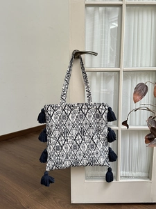 Detail of bohemian canvas tote bag with geometric patterns and navy blue tassels