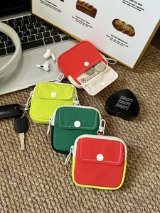 Mini canvas storage pouches with carabiners in various colors on a workspace
