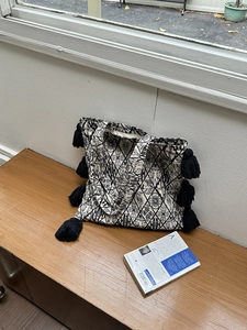 Detailed shot of ethnic canvas tote bag with black and white patterns and side tassels