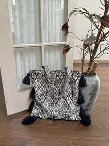 Detail of ethnic canvas tote bag with black tassels and geometric embroidery texture