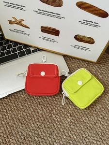 Red and green portable mini pouches with snap buttons and metal hooks on straw mat