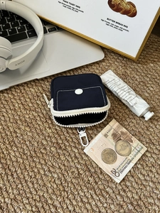 Macro shot of navy canvas mini pouch with white zipper, snap pocket and carabiner hook
