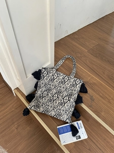 Detailed view of the heavy embroidery patterns and black tassel fringe on the canvas tote