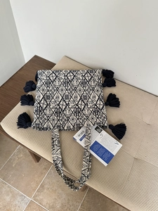 Detail of embroidered canvas tote featuring black geometric patterns and large tassels