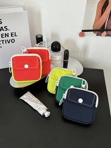 Mini nylon pouches in vivid colors with hooks and snap pockets on a black desk