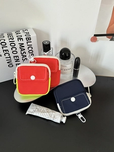 Detailed view of canvas mini pouches with contrast zippers and front button pockets
