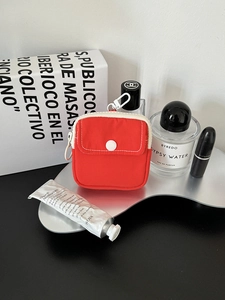 Macro view of compact red canvas pouch with white zipper and functional hanging hook