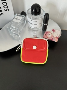 Macro shot of red mini storage pouch with yellow trim and metal snap button on silver tray
