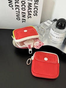 Detail view of red canvas mini coin purse set with white zippers and snap closures
