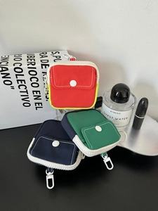 Detailed view of canvas mini coin purses in red, dark green, and navy with white zippers