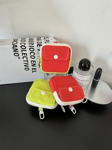 Detail of colorful mini fabric pouches with zipper and metal hook in red and neon green