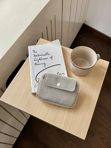 Detail of beige woven mini pouch showing the textured fabric, snap button, and silver zipper