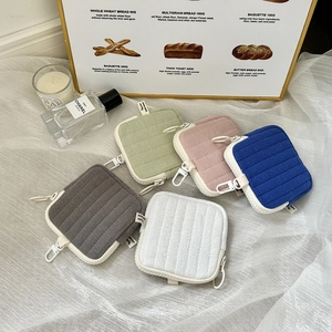 Detailed view of colorful quilted mini earphone pouches with hooks on soft fabric