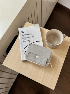 Minimalist canvas storage pouch for data cables and chargers on a wooden stool