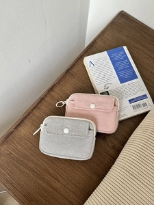 Close-up of pink and grey fabric mini organizers with ring zippers on a wooden desk
