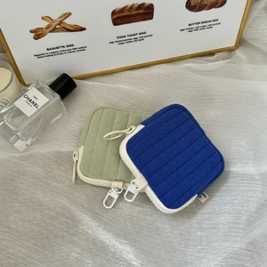 Close-up of quilted mini earphone pouches in sage green and royal blue with metal hooks