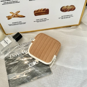 Detailed view of brown quilted mini pouch with white zipper and textured stripe pattern