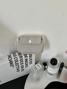 Close-up of a cream canvas mini organizer bag with zipper and snap pocket detail