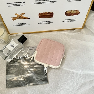 Macro view of pink quilted square earphone pouch with a white carabiner and zipper