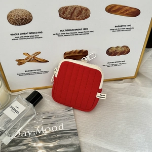 Detailed view of red quilted mini pouch with white hook on stylish lifestyle background