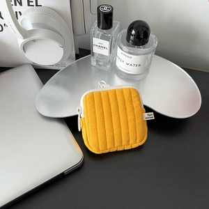 Close-up of yellow quilted mini pouch with zipper and hook for earphones and coins