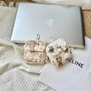 Quilted mini pouches with floral and bear prints on a silver laptop and lace mat