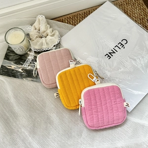 Detailed view of quilted mini storage pouches in pink and yellow with zipper and clip
