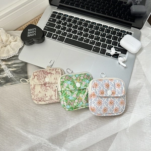 Quilted floral mini pouch with zipper and metal hook for earphones shown on desk