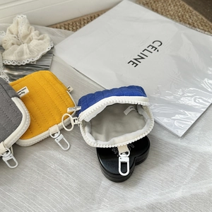 Detailed close-up of quilted mini pouch bags in grey, yellow, and blue with metal hooks