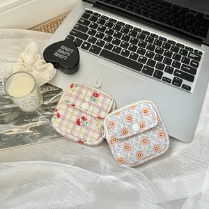 Detailed view of floral canvas earbud pouches with snap buttons and metal hooks