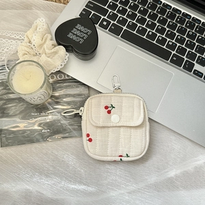 Mini cherry print earphone pouch with snap pocket and metal carabiner on a desk