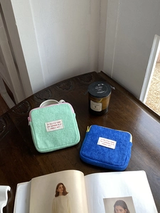 Close-up of soft teddy plush storage pouches in mint green and cobalt blue on a desk